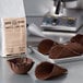 A brown waffle cone made with Carnival King Chocolate Waffle Cone mix sits on a tray next to a bag of chocolate chips.