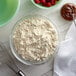 A bowl of flour and a whisk next to a bowl of chocolate spread.