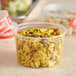 A translucent round plastic deli container filled with food on a counter.