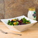 A table set with a CAC Bright White Square Porcelain bowl filled with salad.