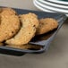 A table with a rectangular black Milano plate filled with cookies.