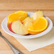 A CAC Corona white porcelain fruit bowl filled with sliced oranges and apples on a table.