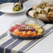 A Visions black plastic catering tray with fruit and sandwiches on a table.