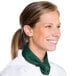 A woman in a white chef's coat wearing a hunter green chef neckerchief.