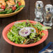 A bowl of salad with shrimp and tomatoes in a GET Rio Orange melamine bowl.