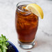 A Libbey Perception beverage glass of iced tea with a lemon wedge.