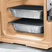 A Cambro Ultra Pan Carrier in coffee beige with a security package holding food pans.