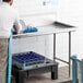 A man using a Regency clean dish table in a commercial kitchen.