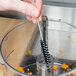 A hand using a Waring cleaning brush to clean a food processor.