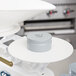 A white Edlund calibration weight on a white scale with a grey lid.
