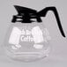 A Grindmaster glass coffee decanter with a black handle and lid on a counter.