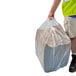 A man in a safety vest holding a large bag of Spilfyter Universal absorbent pads.