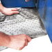 A person using a Spilfyter Streetfyter absorbent pad to clean a floor in a food truck.