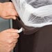 A person's hands putting a plastic bag into a Rubbermaid Slim Jim trash can.