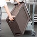 A woman holding a large brown plastic container.