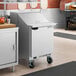 A stainless steel refrigerated sandwich prep table with a single door and a mega top design, equipped with casters for mobility.