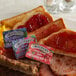 A plate with a piece of bread and Smucker's strawberry jam on a table in a diner.