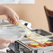 A person holding a Cambro amber high heat spatula over food.