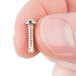 A person holding a small silver Waring screw.