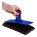 A hand using a blue Scrubble pad holder.