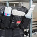 A close up of a black Rubbermaid bag with a white and blue label on a white plastic container inside.