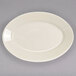 An ivory oval china platter with a rolled edge on a gray surface.