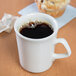 A Homer Laughlin ivory china mug filled with coffee on a table with a muffin.