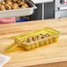 A yellow Carlisle container with food in it.