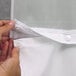 A person's hands attaching a Hookless white shower curtain with a snap ring.