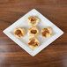 A CAC porcelain dinner plate with four mini pastries on it.