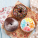 A table with a group of donuts on Choice natural kraft basket liners.