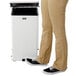 The lower half of a person's legs standing next to a white Rubbermaid medical step can.