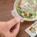 A hand holding a Polar Pak plastic container of salad.