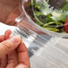 A hand holding a Polar Pak clear plastic bowl filled with salad.