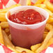 A Solo translucent plastic souffle cup filled with ketchup on a white background.