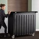 A woman pushing a Cambro black portable bar in a hotel.