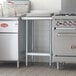 A Regency stainless steel work table with undershelf in a professional kitchen.