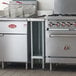 A Regency stainless steel filler table with a backsplash and galvanized undershelf on a counter in a professional kitchen.
