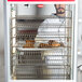 A man in a white coat holding food in a metal rack.