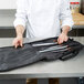 A chef in a white coat holding a Victorinox knife case.