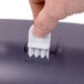 A hand using a white San Jamar Ultrafold towel dispenser on a black table.