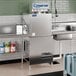 A Jackson Conserver XL-E low temp door type dish machine on a counter in a stainless steel commercial kitchen.