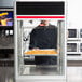 A man standing behind a Hatco countertop food display rack filled with food.