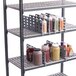 A Cambro Camshelving rack with a shelf divider holding bottles of condiments.