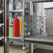 A grey plastic board with holes used as a divider on a Cambro Camshelving® shelf holding a container of ketchup.