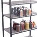 A Cambro Camshelving rack with a shelf divider holding bottles of condiments.
