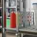 A Cambro Camshelving shelf with containers, condiments, and a shelf divider holding a plastic container and ketchup bottles.