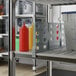 A grey Cambro shelf divider on a shelf with condiment containers.