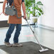 A man in an apron using a Hoover PortaPower vacuum cleaner to vacuum a carpet.