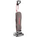 An Oreck upright bagged vacuum cleaner with a grey bag and red and white text on the vacuum.